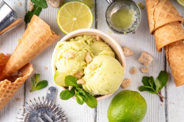 Yaz ferahlatıcı soğuk tatlı, lezzetli aromatik mojito veya limonlu turtalı dondurma, seramik kasede mojito kokteyli aromalı ev yapımı şerbet, taze limon, nane, ahşap zemin üzerinde waffle konileri.