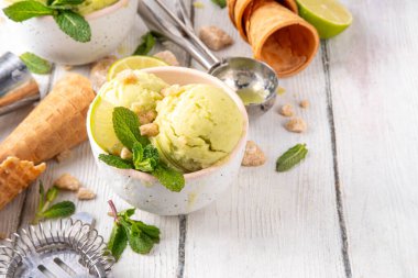 Yaz ferahlatıcı soğuk tatlı, lezzetli aromatik mojito veya limonlu turtalı dondurma, seramik kasede mojito kokteyli aromalı ev yapımı şerbet, taze limon, nane, ahşap zemin üzerinde waffle konileri.