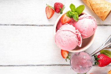 Yaz ferahlatıcı soğuk tatlı, lezzetli ve aromatik çilekli dondurma, seramik kasede ev yapımı meyve şerbeti, taze çilekler, beyaz ahşap arka planda dondurma külahları.