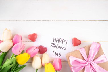 Anneler gününde lale çiçeği buketi, pembe kurdeleli hediye kutusu ve mutlu anneler günü etiketi. Tebrik kartı arkaplanı, poster, broşür, broşür, tanıtım malzemeleri, web sitesi