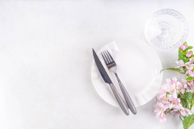 Paskalya bayramı sofrası, çatal bıçak takımı, tabak, bahar ağacı dalları, Paskalya yumurtası ve yuva süsü, beyaz masa arkası fotokopi alanı. Paskalya yemeği daveti, menü geçmişi