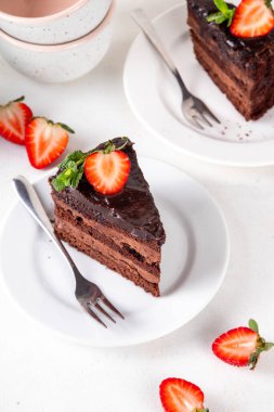 Koyu çikolatalı pasta dilimleri, çikolatalı krema ve çilekli, porsiyonlu tabaklarda, kopyalama alanı