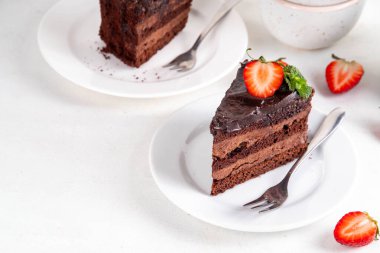 Koyu çikolatalı pasta dilimleri, çikolatalı krema ve çilekli, porsiyonlu tabaklarda, kopyalama alanı