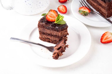 Koyu çikolatalı pasta dilimleri, çikolatalı krema ve çilekli, porsiyonlu tabaklarda, kopyalama alanı