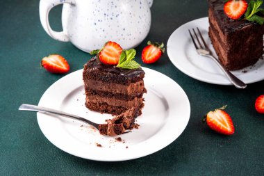 Koyu çikolatalı pasta dilimleri, çikolatalı krema ve çilekli, porsiyonlu tabaklarda, kopyalama alanı