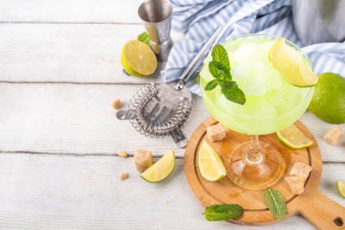Mojito limonata, alkollü buzlu kokteyl, martini bardağında, yaz ferahlatıcı buzlu içecek, votka, limon suyu ve nane şurubu, bardaklarla dolu beyaz bir masada.