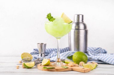 Mojito limonata, alkollü buzlu kokteyl, martini bardağında, yaz ferahlatıcı buzlu içecek, votka, limon suyu ve nane şurubu, bardaklarla dolu beyaz bir masada.