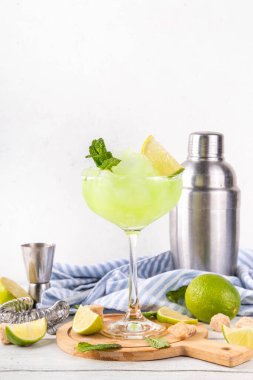 Mojito limonata, alkollü buzlu kokteyl, martini bardağında, yaz ferahlatıcı buzlu içecek, votka, limon suyu ve nane şurubu, bardaklarla dolu beyaz bir masada.