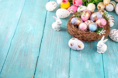 Paskalya yuvaları ve bahar çiçekli yumurtalar, Mutlu Paskalya bayramı tebrik kartları tahta arka planda yatıyordu, üst görünüm kopyalama alanı