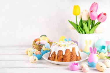 Geleneksel Paskalya pastası şekerleme ve şekerle süslenmiş, şenlikli ruh dekorasyonu ve çiçek buketiyle süslenmiş. Paskalya kutlamaları pastel renkli Paskalya yumurtaları ve tavşan tavşanlarıyla dolu tatil masası.