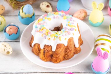 Geleneksel Paskalya pastası şekerleme ve şekerle süslenmiş, şenlikli ruh dekorasyonu ve çiçek buketiyle süslenmiş. Paskalya kutlamaları pastel renkli Paskalya yumurtaları ve tavşan tavşanlarıyla dolu tatil masası.