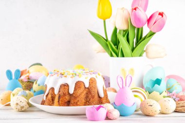 Geleneksel Paskalya pastası şekerleme ve şekerle süslenmiş, şenlikli ruh dekorasyonu ve çiçek buketiyle süslenmiş. Paskalya kutlamaları pastel renkli Paskalya yumurtaları ve tavşan tavşanlarıyla dolu tatil masası.