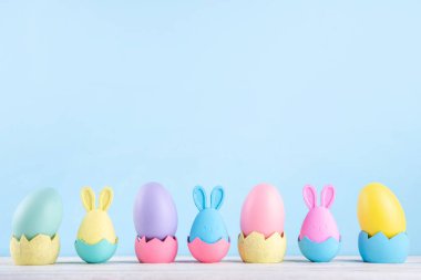 Paskalya geleneği, Paskalya yumurtası avı hazırlığı, çocuk partisi geçmişine davetiye. Renkli dekorasyon tavşanları ve çimlerde Paskalya yumurtaları ve mavi arkaplan, boşluğu kopyala