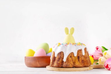 Geleneksel Paskalya pastası şekerleme ve şekerle süslenmiş, şenlikli ruh dekorasyonu ve çiçek buketiyle süslenmiş. Paskalya kutlamaları pastel renkli Paskalya yumurtaları ve tavşan tavşanlarıyla dolu tatil masası.