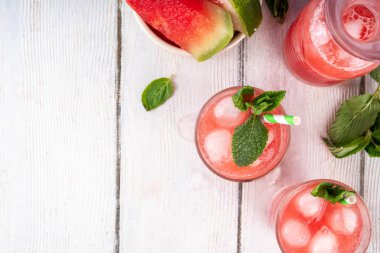 Ev yapımı karpuz limonatası, ferahlatıcı tatlı yaz içeceği, naneli buzlu karpuz suyu ve çizgili kamış, açık mavi ve ahşap arka plan, kopyalama alanı. 