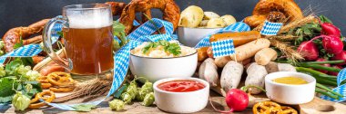 Oktoberfest holiday greeting card, menu, invitation background, Traditional Oktoberfest festival food, bavarian sausages, pretzels, potato, sauerkraut, beer mug on wooden background, banner format
