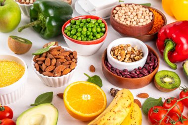 Portföy diyeti, fındık, sebze proteini, bitki sterolleri, yapışkan lif, fasulye, baklagiller, taze sebzeler ve beyaz arka plandaki meyveler dahil olmak üzere dengeli kolesterol vejetaryen gıdalar.