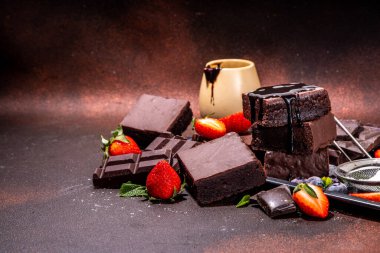 Böğürtlenli siyah çikolatalı kek. Üzerine çikolata sosu serpiştirilmiş ev yapımı kek kurabiyeleri ve koyu arkaplanda taze çilek, yabanmersini, fotokopi alanı.