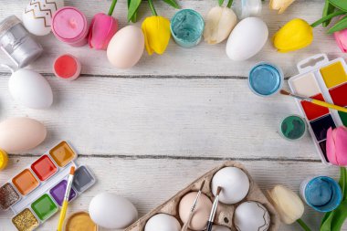 Aile gelenekleri, Paskalya hazırlıkları. Bahar çiçeği laleleri, dekoratif Paskalya yumurtaları boyalı, fırçalı, aksesuarlı beyaz ahşap arka planda yumurta çizip boyamak için aksesuarlar.