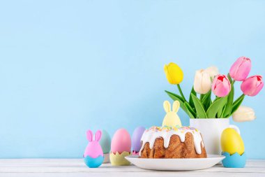 Geleneksel Paskalya pastası şekerleme ve şekerle süslenmiş, şenlikli ruh dekorasyonu ve çiçek buketiyle süslenmiş. Paskalya kutlamaları pastel renkli Paskalya yumurtaları ve tavşan tavşanlarıyla dolu tatil masası.