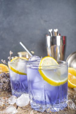 Lavanta alkollü kokteyl, limonlu ve ballı Lavandula limonatası lavanta demeti ve barmen aletleriyle ahşap arka planda, kopyalama alanı.
