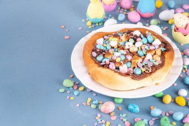 Tatlı Paskalya tatlı pizzası, çikolata soslu, marşmelov ve çikolatalı yumurta, Paskalya bayramı çocukları için atıştırmalık, şenlikli süslemeler, renkli yumurtalar ve tavşan tavşanlı.