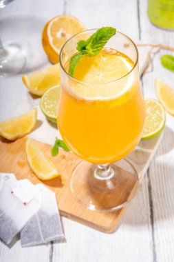 Modaya uygun çay seti yeşil, oolong, siyah, çay ve diğer çay karışımlarından esinlenilmiştir. Soda, şerbetli soğuk yaz içecekleri, limon, kireç ve nane, güneşli beyaz ahşap arka plan.