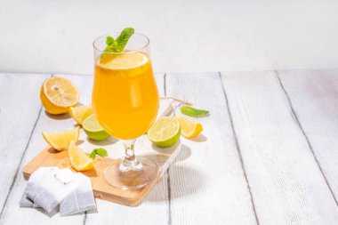 Modaya uygun çay seti yeşil, oolong, siyah, çay ve diğer çay karışımlarından esinlenilmiştir. Soda, şerbetli soğuk yaz içecekleri, limon, kireç ve nane, güneşli beyaz ahşap arka plan.