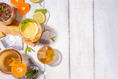 Modaya uygun çay seti yeşil, oolong, siyah, çay ve diğer çay karışımlarından esinlenilmiştir. Soda, şerbetli soğuk yaz içecekleri, limon, kireç ve nane, güneşli beyaz ahşap arka plan.