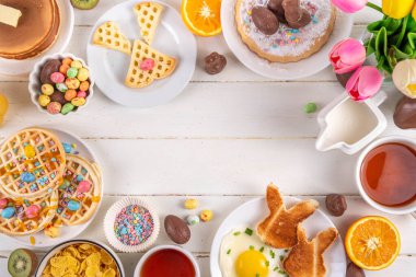 Paskalya tatili tatlı kahvaltı, brunch. Paskalya süslü Belçika waffle 'ları, krepler, kahvaltı gevrekleri ve süt, kızarmış yumurtalar kızarmış ekmek ve pastırma, Paskalya çikolatalı yumurtalar ve bahar çiçekleriyle birlikte tavşan.