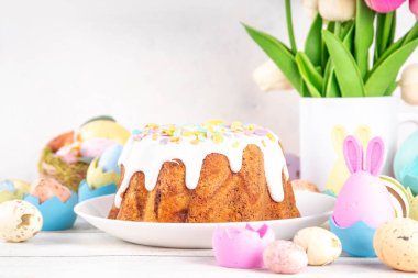 Geleneksel Paskalya pastası şekerleme ve şekerle süslenmiş, şenlikli ruh dekorasyonu ve çiçek buketiyle süslenmiş. Paskalya kutlamaları pastel renkli Paskalya yumurtaları ve tavşan tavşanlarıyla dolu tatil masası.