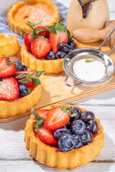 Yaz meyveli mini tart kekleri. Porsiyonlu vanilyalı tatlı bardakları taze çilek, yabanmersini, ahududu, beyaz ahşap arka plan fotokopi alanı