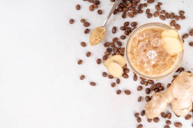 Soğuk zencefilli kahve fincanı. Beyaz zemin üzerinde zencefil tozu ve zencefil kökü olan kremalı buzlu içecek. Sağlıklı sıcak içecek. alternatif tıp, çare 