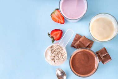 Hızlı ve basit protein pudingi. Sağlıklı yaz soğuk tatlısı. Üç bardak vanilyalı, çikolatalı ve çilekli puding, çikolata dilimleri, taze çilek, yabanmersini, protein tozu