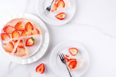Japon yağmur damlası keki, ya da Mizu Shingen Mochi, berrak jöle tatlısı, kristal berrak su benzeri lezzetli, çilek dilimli tart, tabaklar üzerine porsiyonlu, beyaz mermer arka plan fotokopi alanı