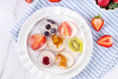 Japon yağmur damlası keki, ya da Mizu Shingen Mochi, berrak jöle tatlısı, kristal berraklığında meyve ve böğürtlen dilimli agar pudingi, tabakta porsiyonlu, beyaz mermer arka plan fotokopi alanı