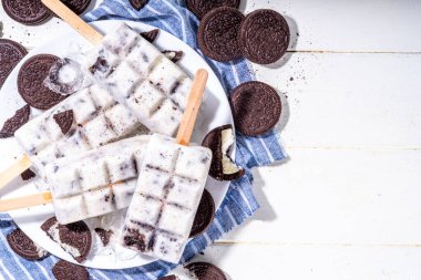 Krema ve kurabiye dondurması, vanilyalı dondurma lolipoplar çikolatalı ezilmiş kurabiyeler, mutfak masasında bir sürü kurabiye.