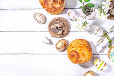 Geleneksel tatil pastaları ile Paskalya pastaları - Kraffin, panettone, paska kulich, Paskalya yumurtaları, beyaz ahşap masa üzerinde bahar çiçekleri, bahar bayramı Paskalya tebrik kartı arka planı