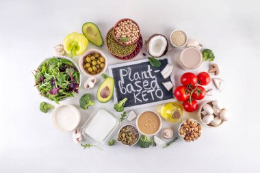 Bitki bazlı keto gıda arka planı, düşük karbonhidratlı vejetaryen keto diyet malzemeleri, sağlıklı vejetaryen yağ ve protein kaynağı. Çeşit çeşit yeşil sebzeler, fındık, baklagiller, yağ, hindistan cevizi, fıstık, fıstık ezmesi