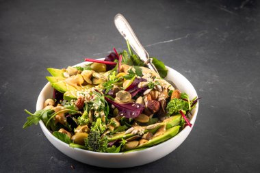 Bitki temelli keto yiyecekler, düşük karbonhidratlı vegan salatası çeşitli yeşil sebzeler, avokado, roka, ıspanak, marul, beyaz peynir, fındık, fıstık, fıstık ezmesi, avokado ve zeytin.