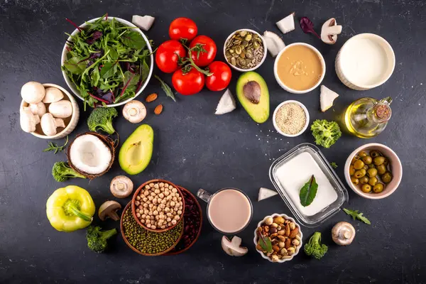 Bitki bazlı keto gıda arka planı, düşük karbonhidratlı vejetaryen keto diyet malzemeleri, sağlıklı vejetaryen yağ ve protein kaynağı. Çeşit çeşit yeşil sebzeler, fındık, baklagiller, yağ, hindistan cevizi, fıstık, fıstık ezmesi