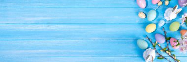 İlkbahar Paskalya bayramı üst manzaralı düz arka planda yumurtalar, tavşanlar ve bahar çiçekleri yatar. Kopya alanı olan parlak renkli tebrik kartı arkaplanı.