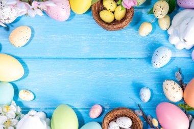 İlkbahar Paskalya bayramı üst manzaralı düz arka planda yumurtalar, tavşanlar ve bahar çiçekleri yatar. Kopya alanı olan parlak renkli tebrik kartı arkaplanı.