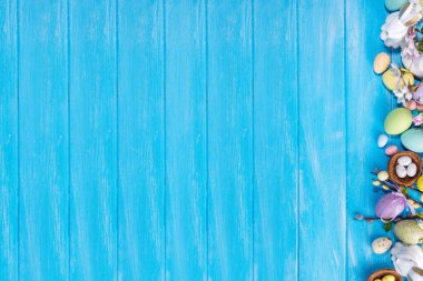 İlkbahar Paskalya bayramı üst manzaralı düz arka planda yumurtalar, tavşanlar ve bahar çiçekleri yatar. Kopya alanı olan parlak renkli tebrik kartı arkaplanı.