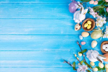 İlkbahar Paskalya bayramı üst manzaralı düz arka planda yumurtalar, tavşanlar ve bahar çiçekleri yatar. Kopya alanı olan parlak renkli tebrik kartı arkaplanı.