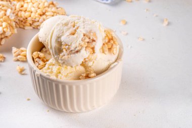 Pirinç gevreği dondurmayı, gevrek vanilyalı dondurmayı portakal kaselerinde, beyaz masa arkasında bolca pirinç gevreğiyle ikram eder.