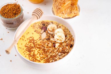 Arı polenli, altın kremalı ya da meyveli, granola ve muzlu sağlıklı meyve suyu kasesi. Temiz yemek, diyet vejetaryen yemeği ve arı poleni organik tozu. 