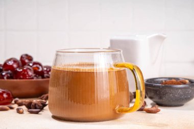 Sağlıklı organik hurma tohumu kahve, rendelenmiş hurma tohumlarıyla yapılmış kahve fincanı, bej arka planda bütün hurma meyveleri ve tohumlarla. Alternatif sıcak kahve.