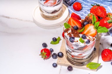 Çilekli tatlı, katmanlı parfe tatlı çikolatalı bisküvi, çırpılmış krema ve taze böğürtlen. Bardakta yaz kahvaltısı tatlısı