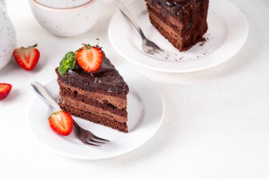 Koyu çikolatalı pasta dilimleri, çikolatalı krema ve çilekli, porsiyonlu tabaklarda, kopyalama alanı
